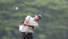 Bubba Watson strikes a wedge shot, whilst a divot flies into the air