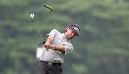 Bubba Watson strikes a wedge shot, whilst a divot flies into the air