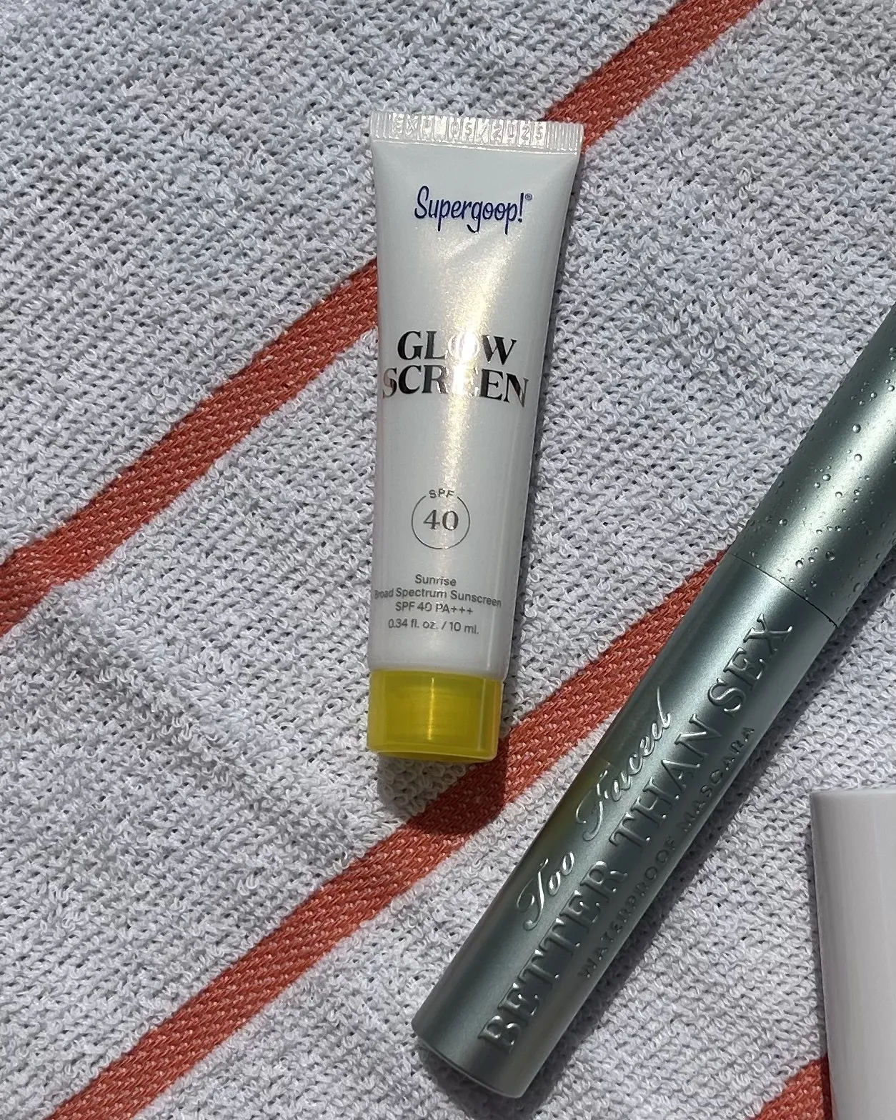 Supergoop! Glowscreen lying on a beach towel.