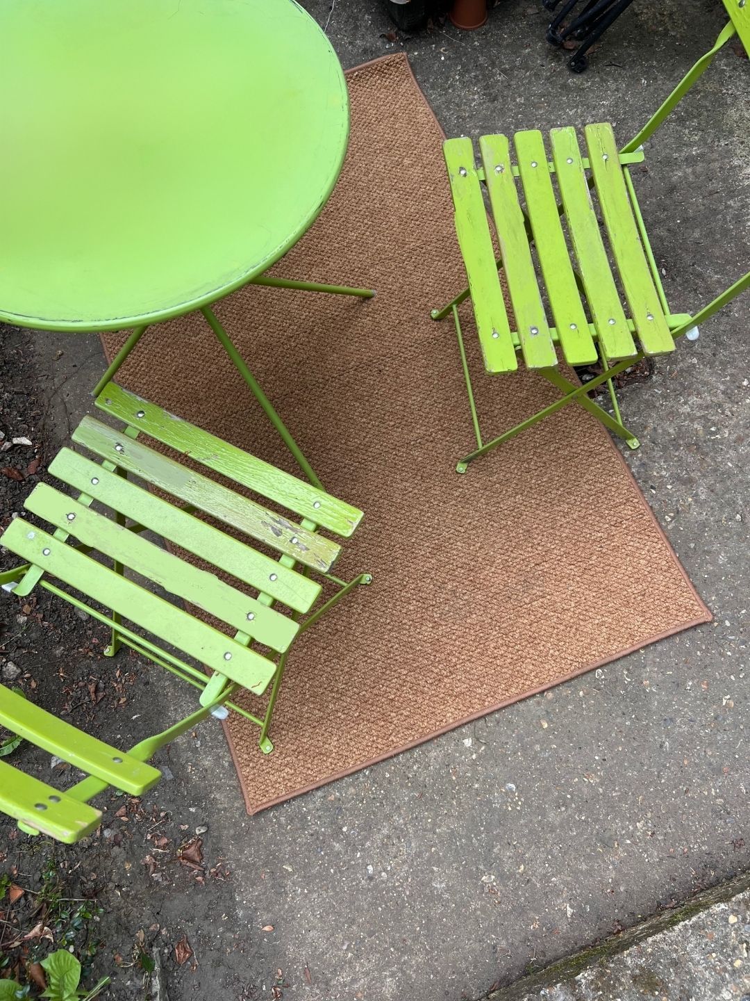Image of a jute-inspired outdoor rug on a dark stone patio with a lime green bistro set.
