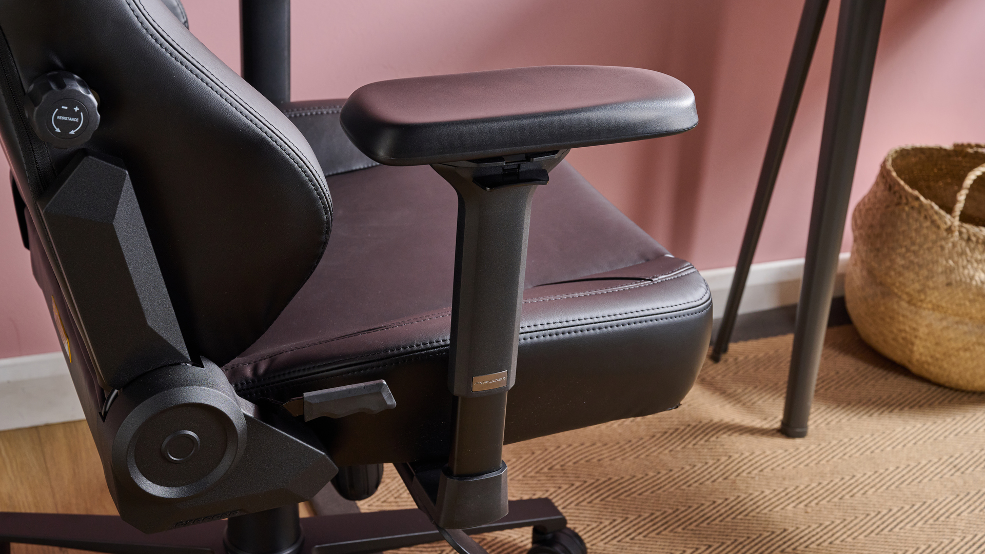 Close-up of right arm rest on DXRacer Craft with floor and pink wall in background