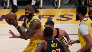 LeBron James #23 of the Los Angeles Lakers controls the ball as Draymond Green #23 and Stephen Curry #30 of the Golden State Warriors defend during the first half of an NBA Tournament Play-In game at Staples Center on May 19, 2021 in Los Angeles, California.