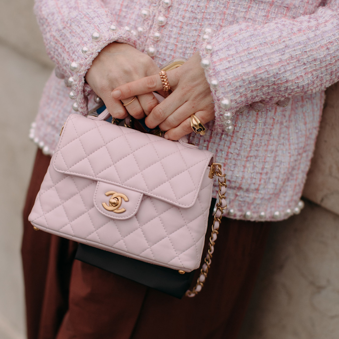 a woman holding a pink Chanel bag with a Chanel jacket in Paris