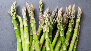 Stems of asparagus sitting on a stone countertop, one of the gut-healthy foods to eat