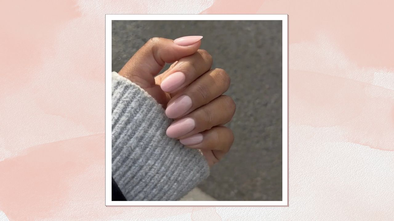 A close-up of a hand with pastel pink almond nails, created by nail artist Julia Diogo (@paintedbyjools)/ featured in a pink watercolour paint-style template