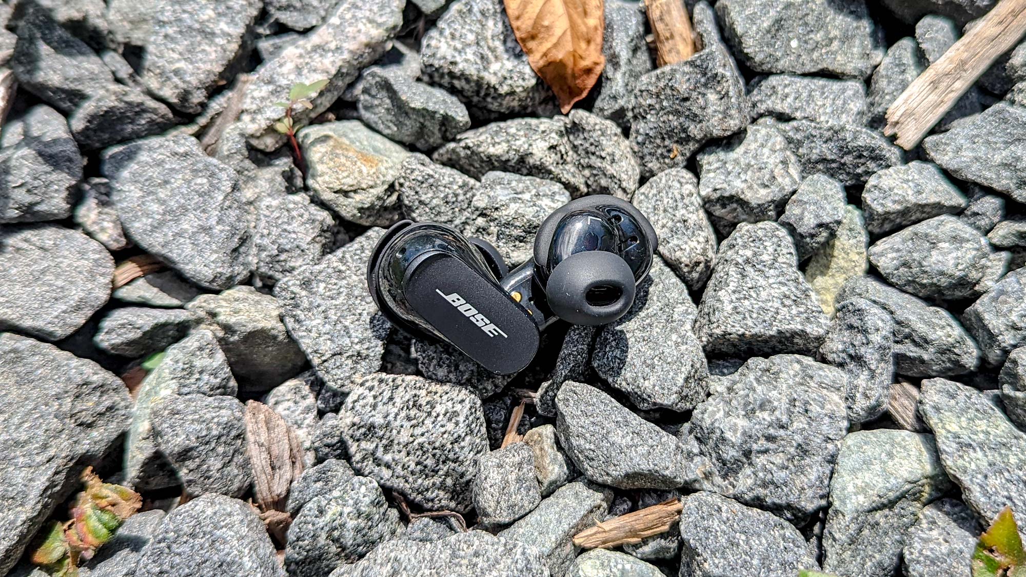 Bose QuietComfort Earbuds 2 placed amongst some grey stones
