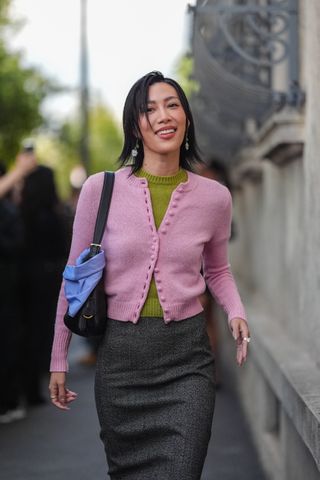 Woman in green top, pink cardigan, and dark gray skirt.