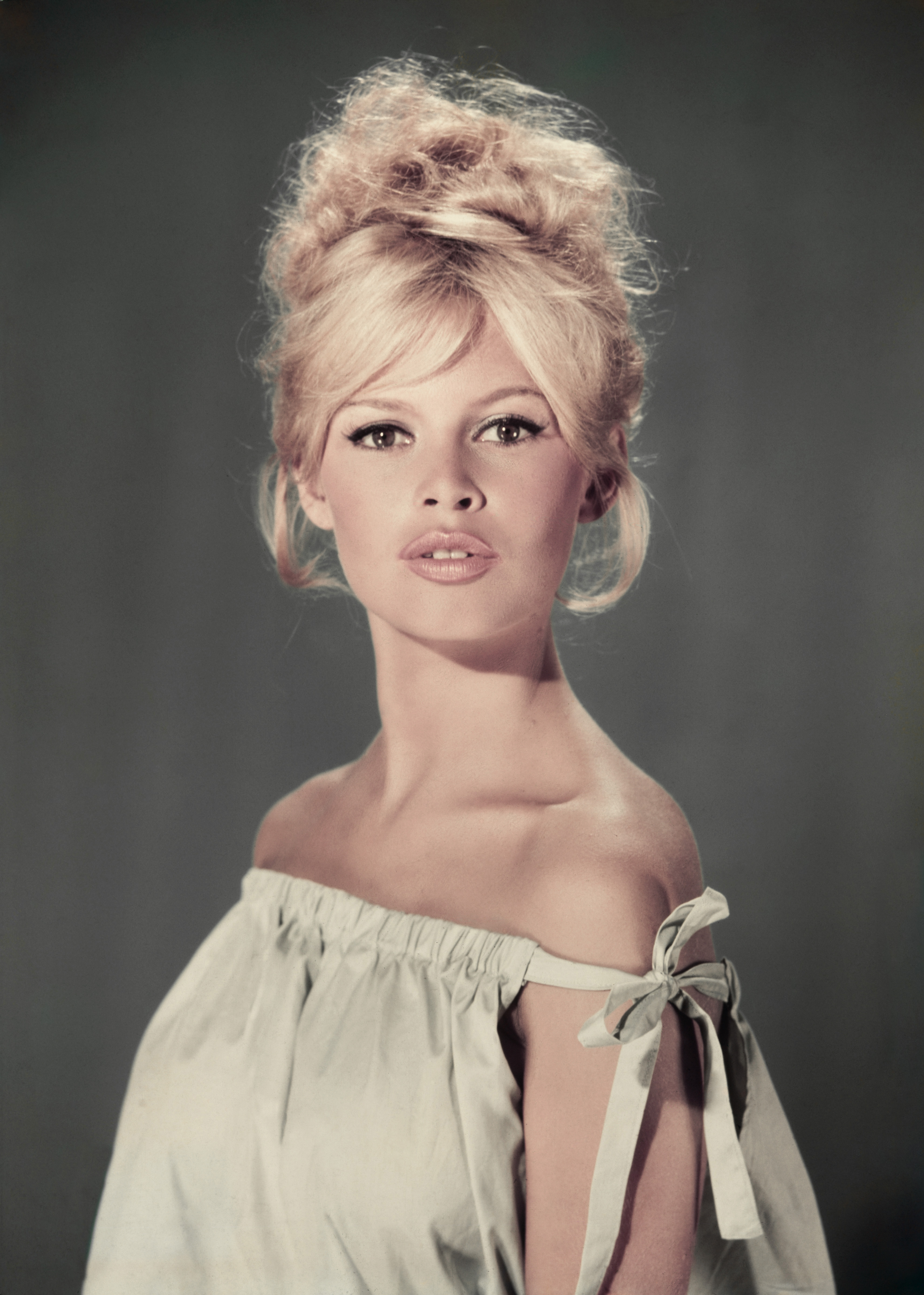 Studio portrait of actor and model Brigitte Bardot wearing a light blue off-the-shoulder dress.