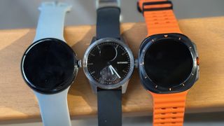 The Google Pixel Watch 3, Withings ScanWatch 2, and Samsung Galaxy Watch Ultra sitting side-by-side on top of a chair armrest.