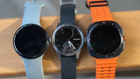 The Google Pixel Watch 3, Withings ScanWatch 2, and Samsung Galaxy Watch Ultra sitting side-by-side on top of a chair armrest.