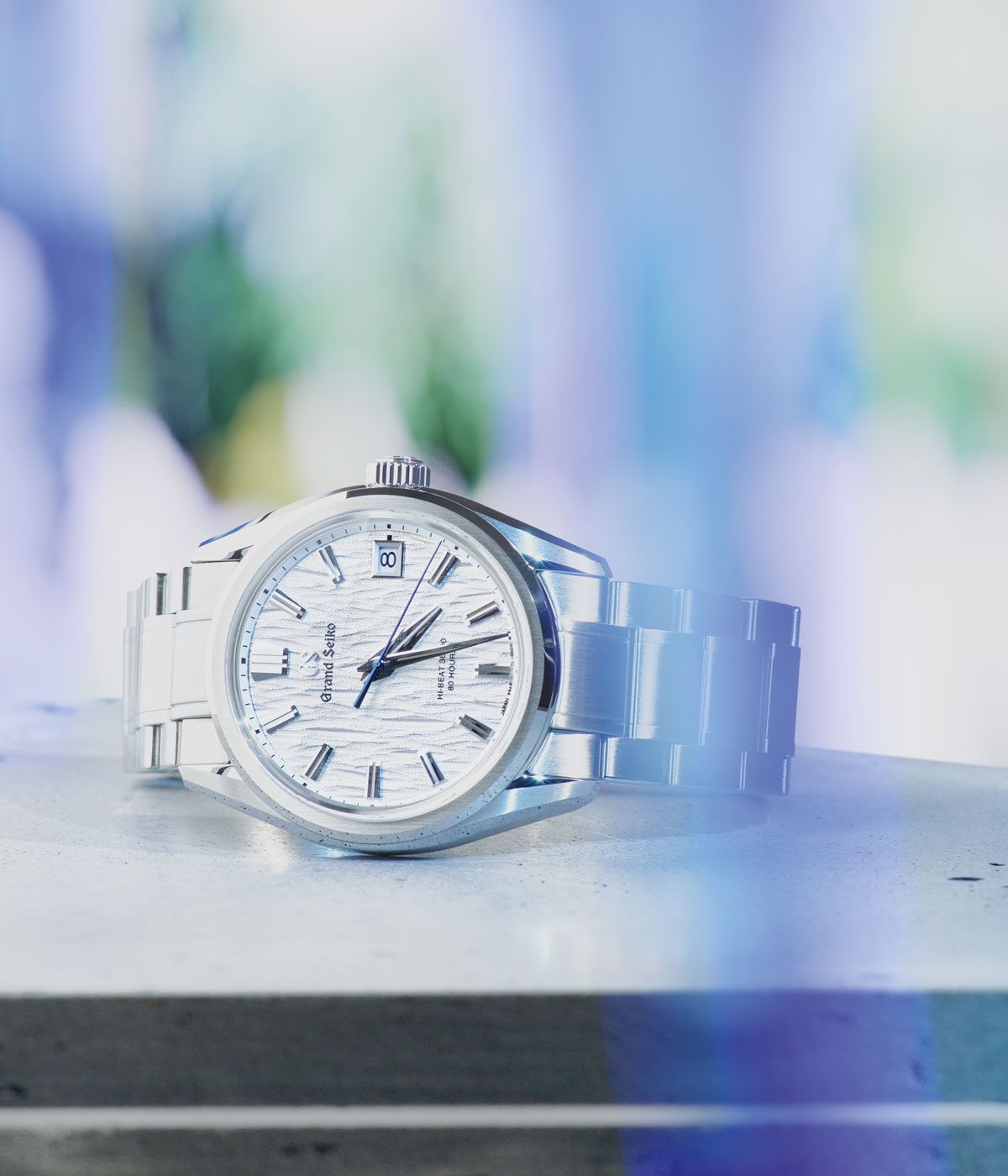 Seiko watch with a steel strap and white dial against a grey background 