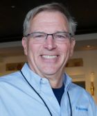 Headshot of Ken Nelson in light blue shirt in front of out-of-focus interior home background