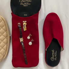 Flat lay image of red Carven slippers with pearl and watch.