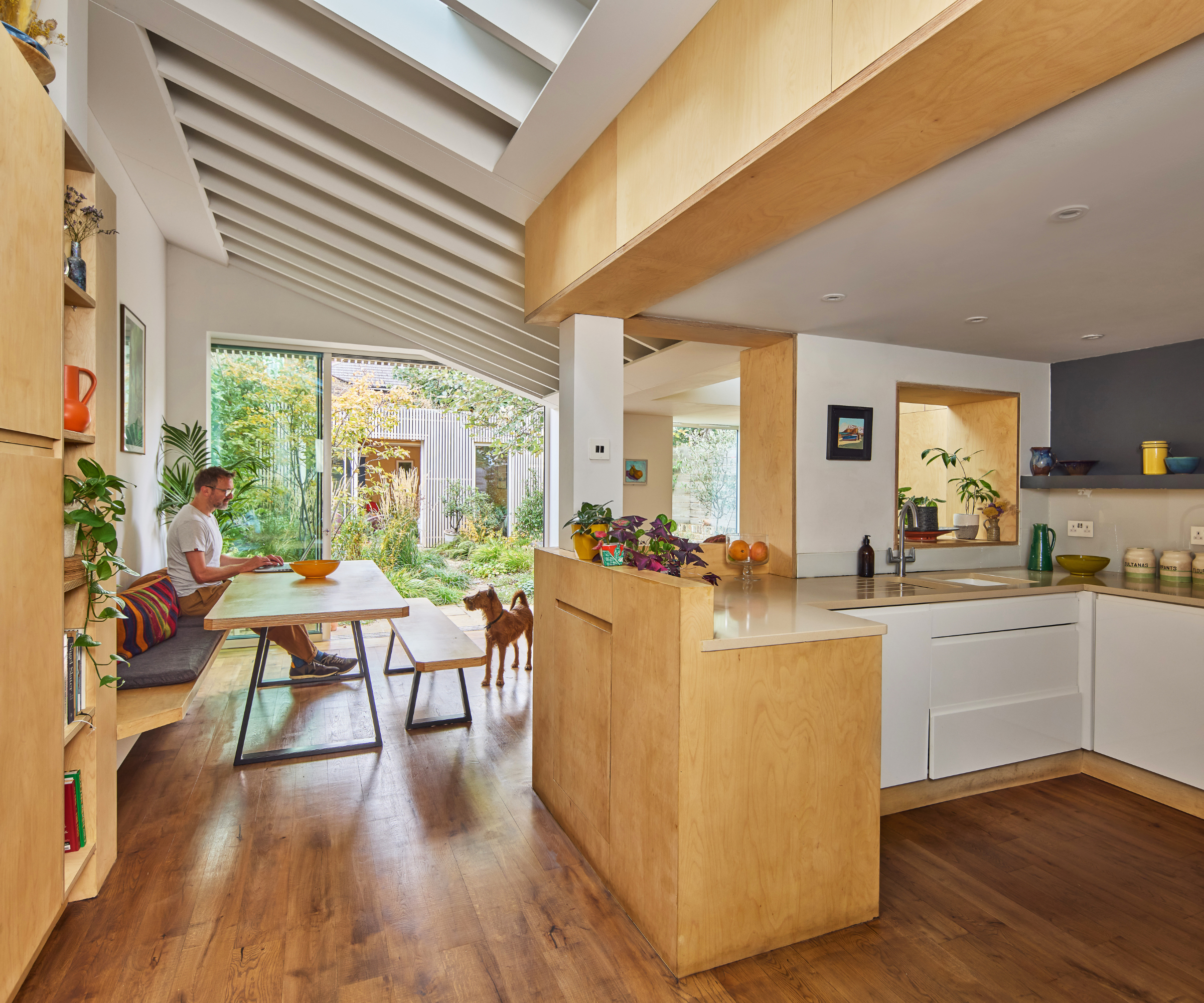 Open plan kitchen diner with wooden floor, beamed ceiling, and view into the garden from the patio doors 