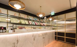 Ladurée outlet in the JNĉQUOI luxury restaurant. A marble countertop is to the left, with the chandeliers above it.