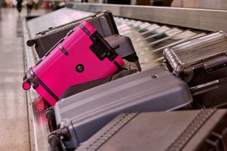 Image of a smart suitcase in pink color lying on a conveyor belt