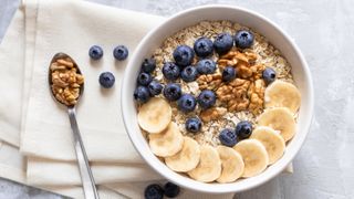 a bowl of oats topped with chopped banana, blueberries and walnuts