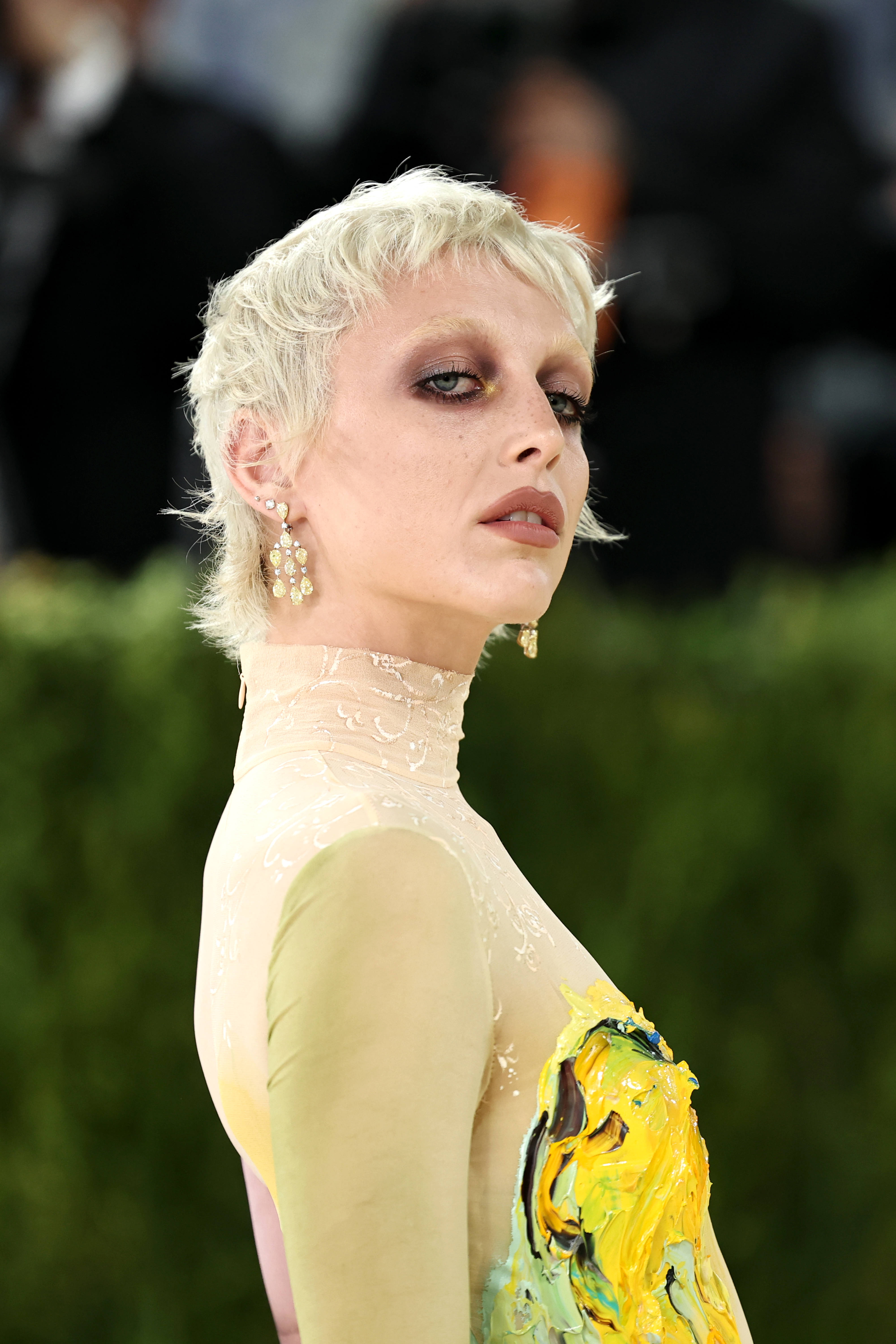 a woman with a platinum pixie cut and light yellow turtleneck dress