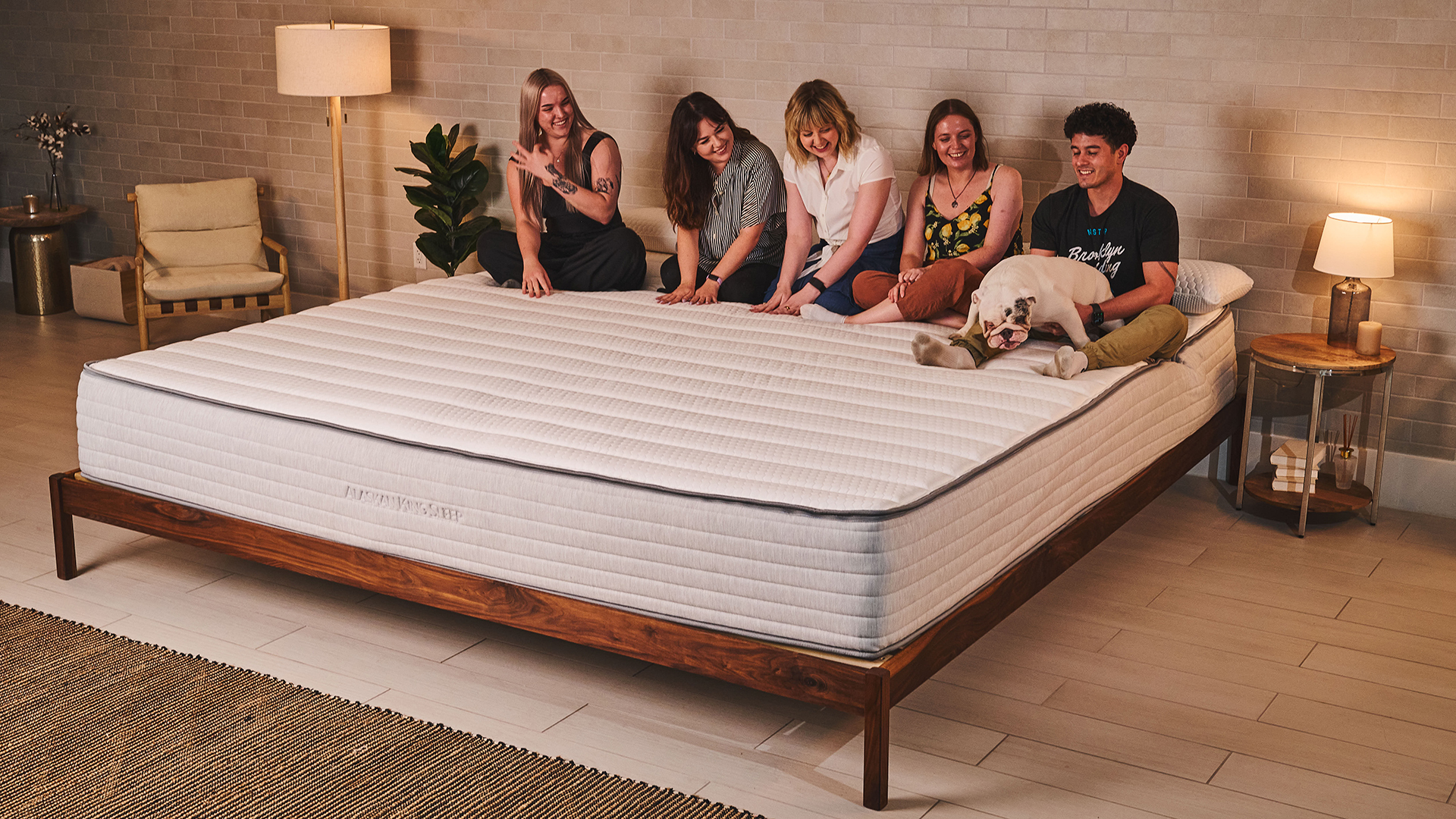 Five people and a dog sit at the head of a Nolah Luxe Alaskan king mattress in a bedroom, showing how large this oversized mattress is