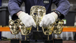 A metalworker holds one of the finished masks during the BAFTA "Making of the Mask" photocall, which shows the process of how the iconic mask is made, at the FSE Foundry on February 24, 2024 in Braintree, England.
