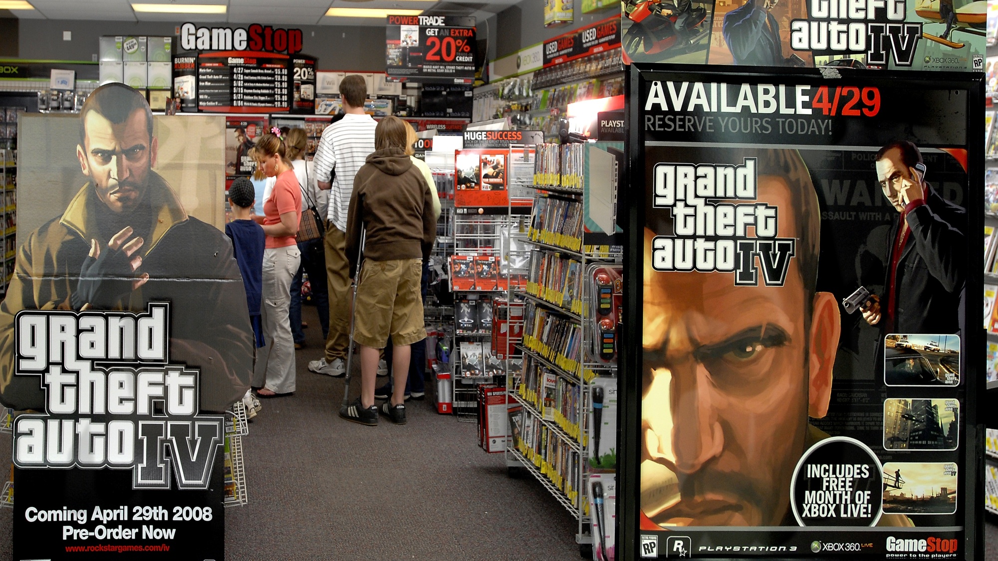 Grand Theft Auto 4 on sale at midnight, as GameStop at Maine Crossing Mall has many promotional posters for the event and frame a crowd of people buying games.