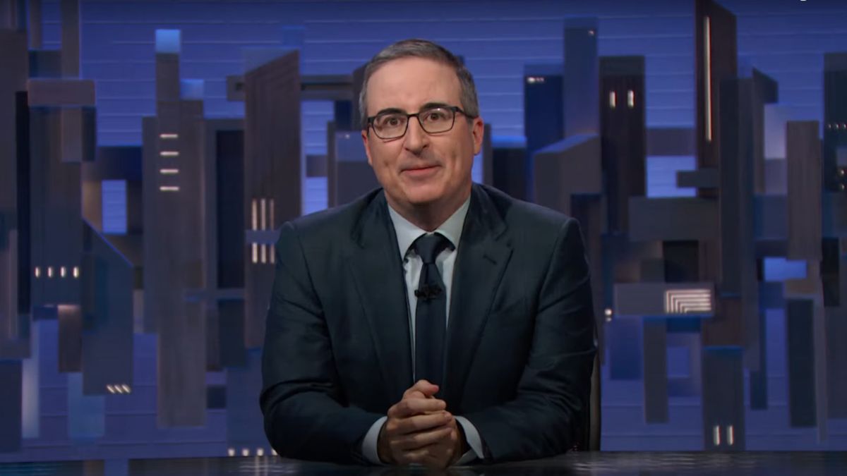 John Oliver sitting at his desk, introducing a segment on Last Week Tonight with John Oliver.