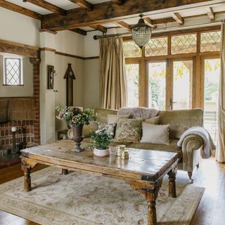 A country living room with wooden beams, a wooden coffee table and a rug