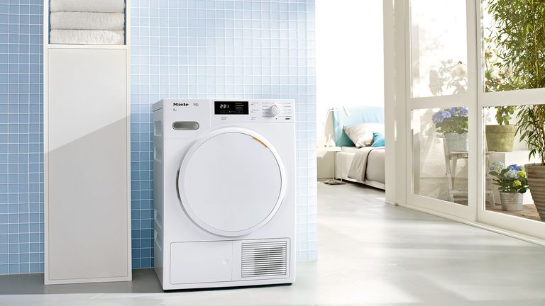 One of the best tumble dryers in a blue tiled room near a bedroom