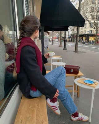 Woman wearing black blazer, jeans, burgundy sweater, burgundy shoes, and burgundy socks.