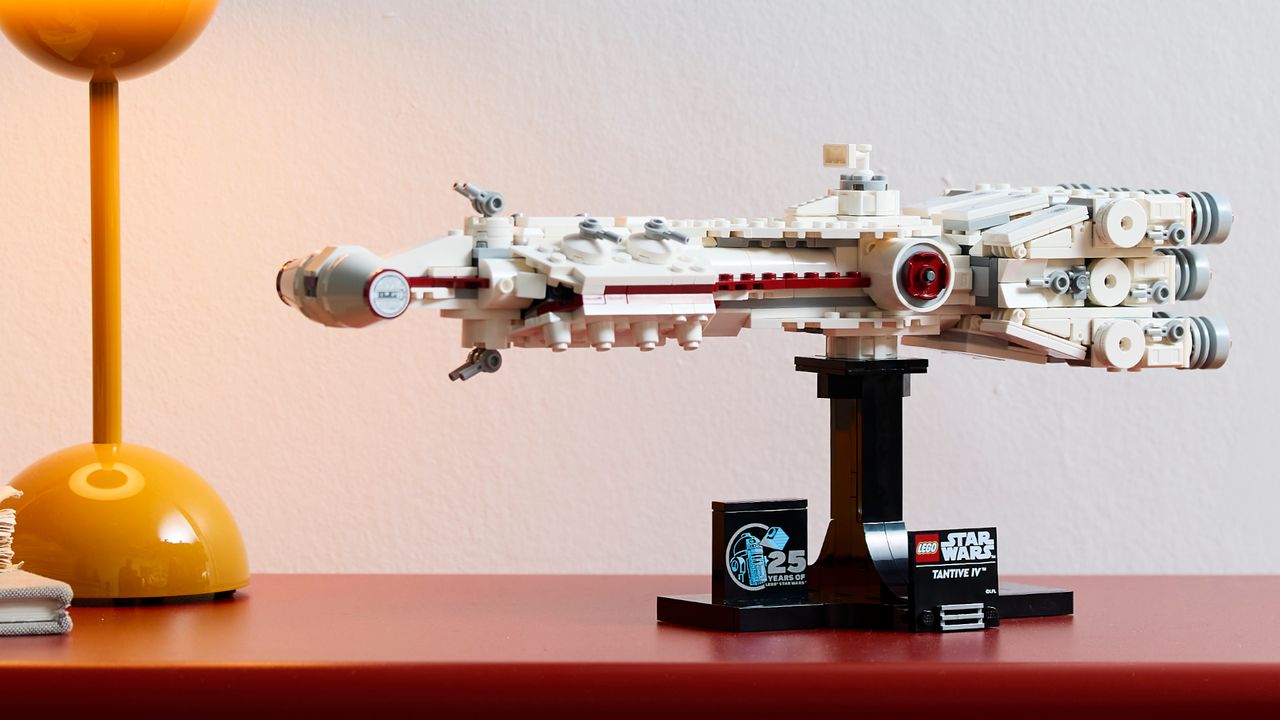 Lego Tantive IV on a red surface beside a yellow lamp