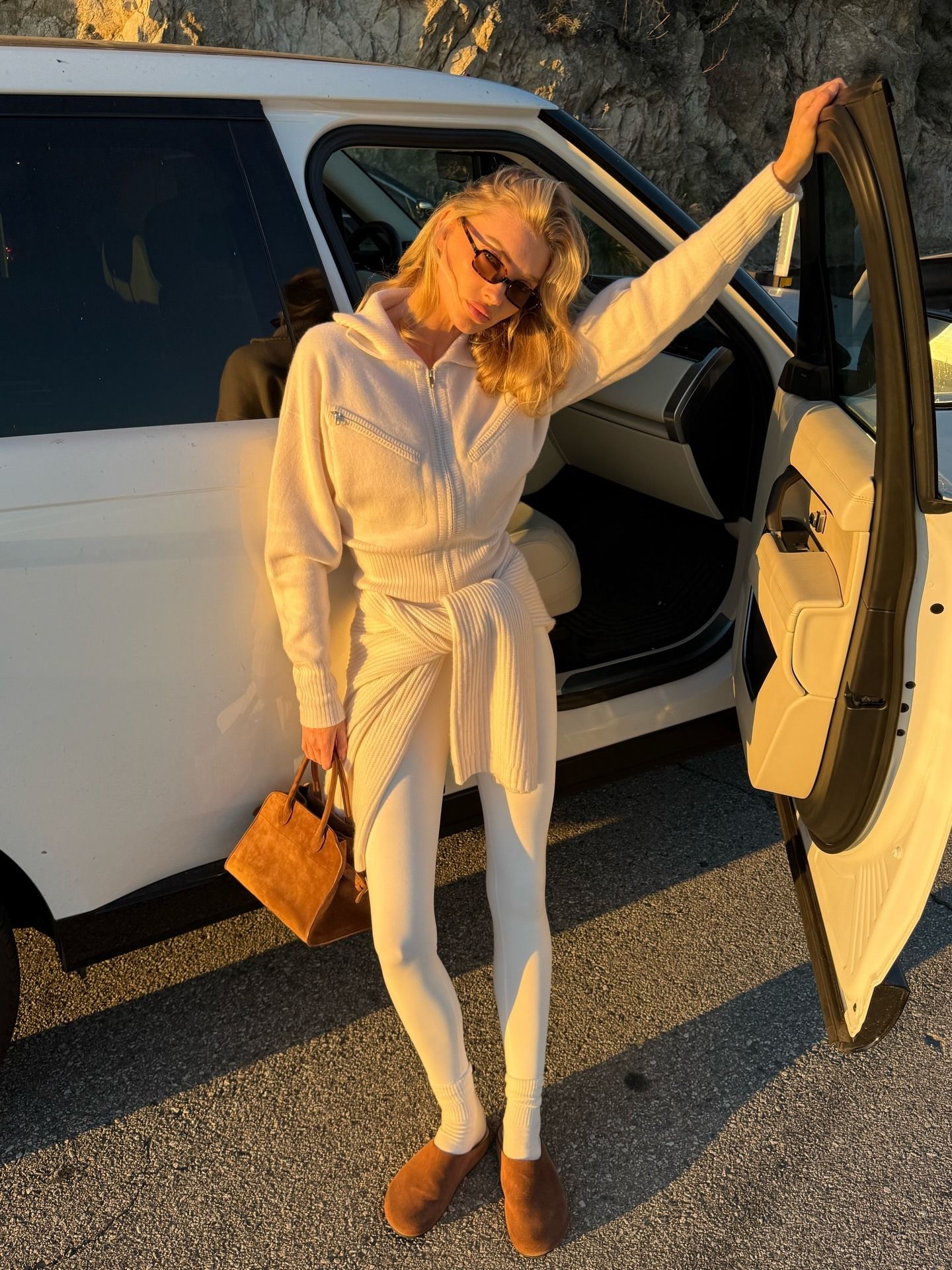 Elsa Hosk wearing crew sweaters, white leggings, and The Row bag and shoes