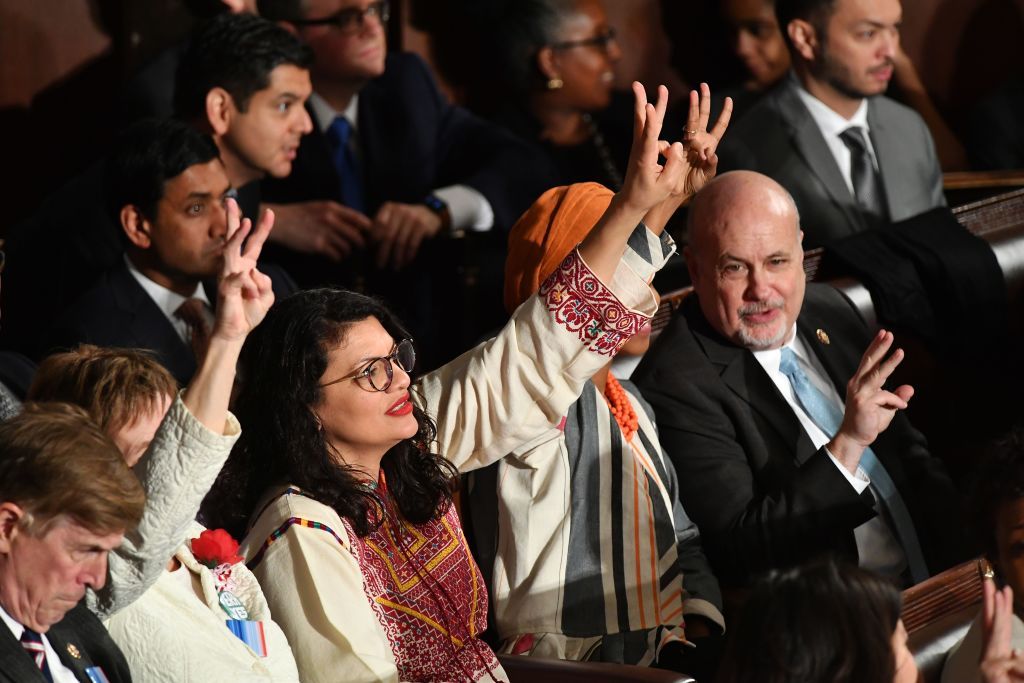 Democratic lawmakers hold up three fingers.