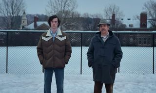 dominic sessa and paul giamatti stand in the snow in the holdovers