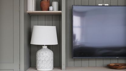 A grey media unit with a TV and a table lamp