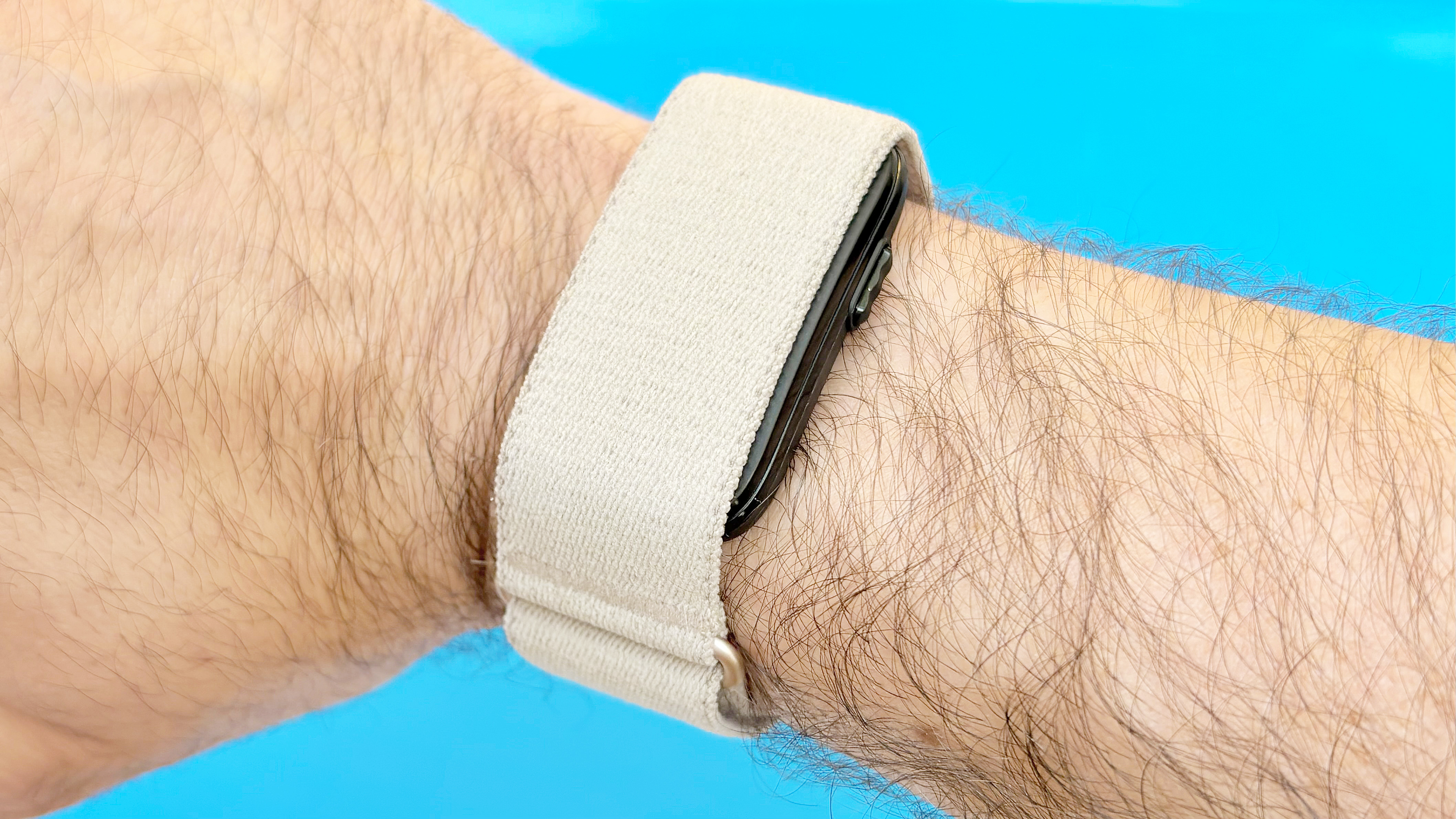 Close-up of the Garmin Cirqa on the reviewer's wrist against a blue background