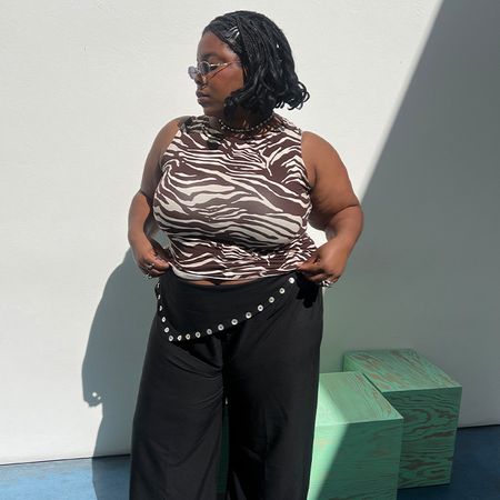 Chichi wears zebra print ref tank and black pants while posing. 