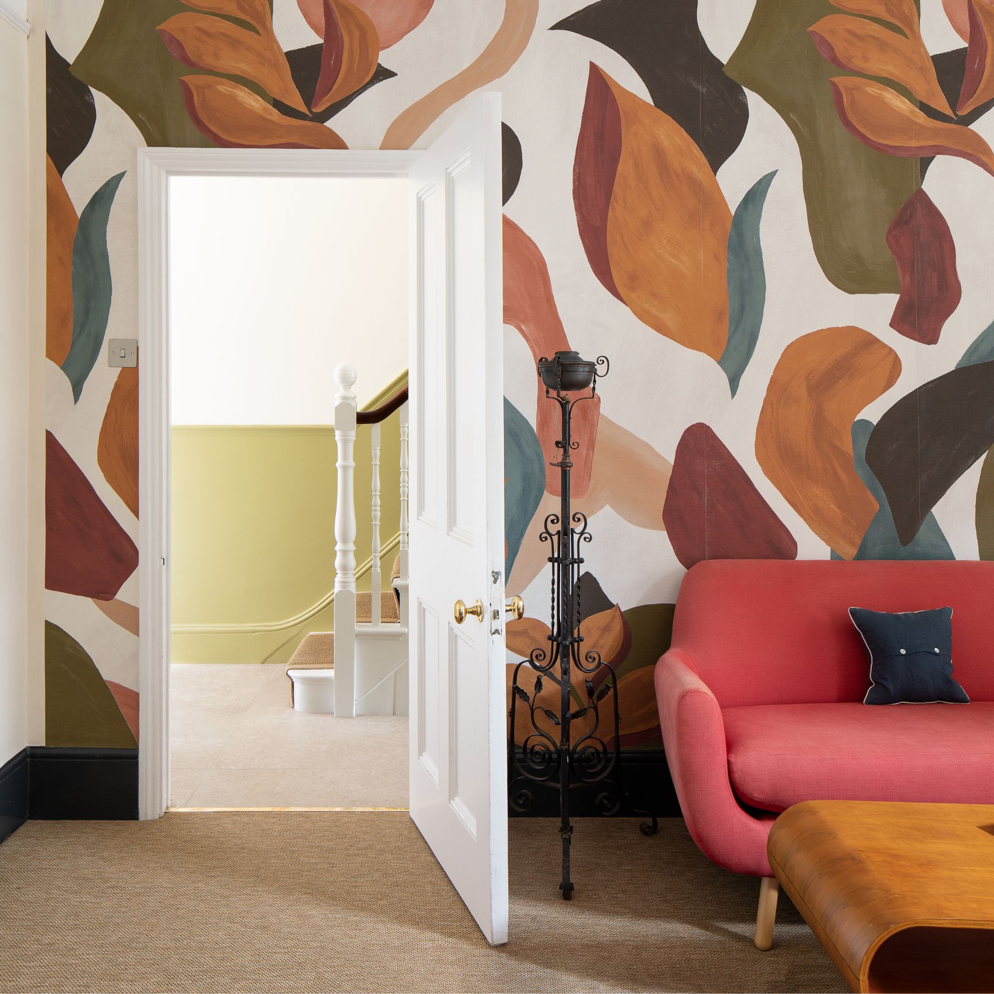Interior of garage conversion by Resi. Space is converted into a living area with bold wallpaper and colourful sofa