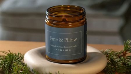 The Natuepedic Pine & Pillow Candle on a nightstand. 