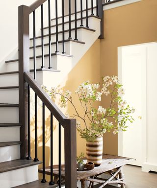 Small hallway painted in earthy yellow, staircase with risers in white and white landing