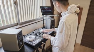 Man wearing a white shirt DJs in his bedroom