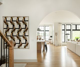 modern neutral entryway with an arched opening next to a modern pierre frey tapestry wall hanging