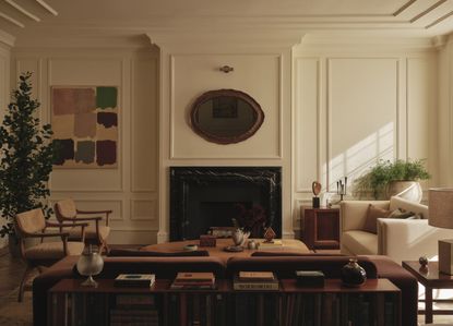 a living space with multiple sofas and chairs with white panelled walls