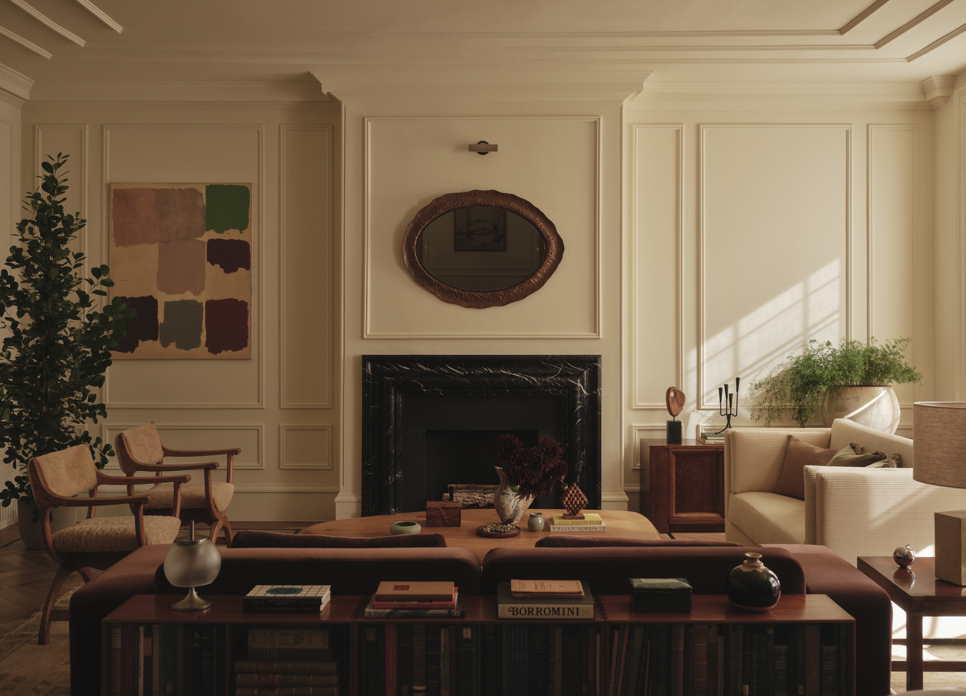 a living space with multiple sofas and chairs with white panelled walls