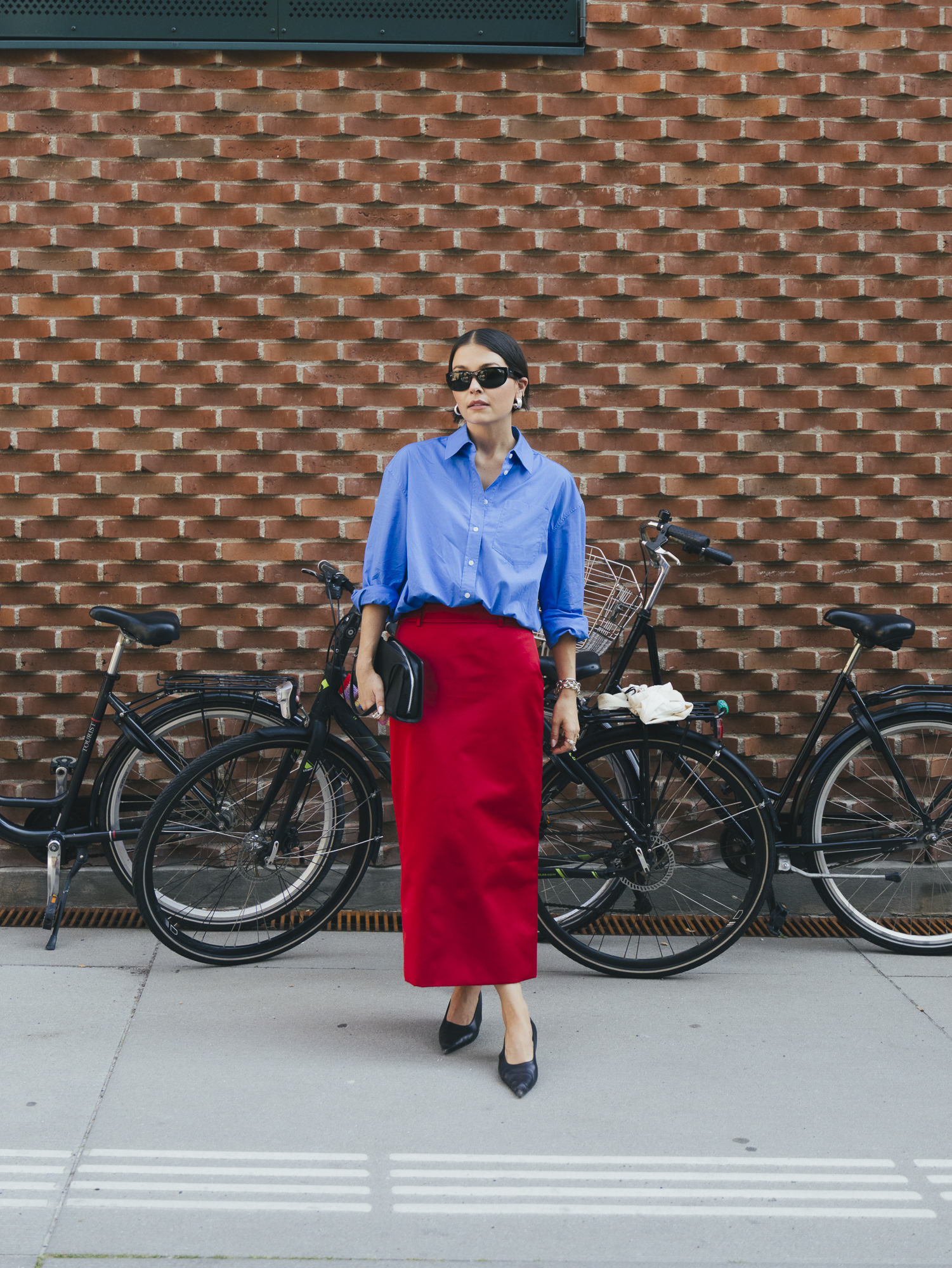 a woman wears a red skirt and a blue button-down shirt.