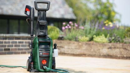 Bosch Aquatak pressure washer in promotional image being used in garden