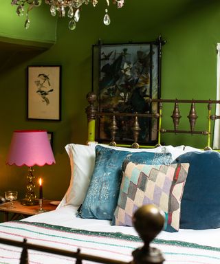 vibrant green painted bedroom with wrought iron bed frame and mixed scatter cushions