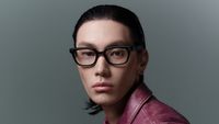 A model wearing black-framed smart glasses with built-in camera sensors looking directly at the camera.