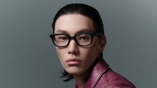 A model wearing black-framed smart glasses with built-in camera sensors looking directly at the camera.