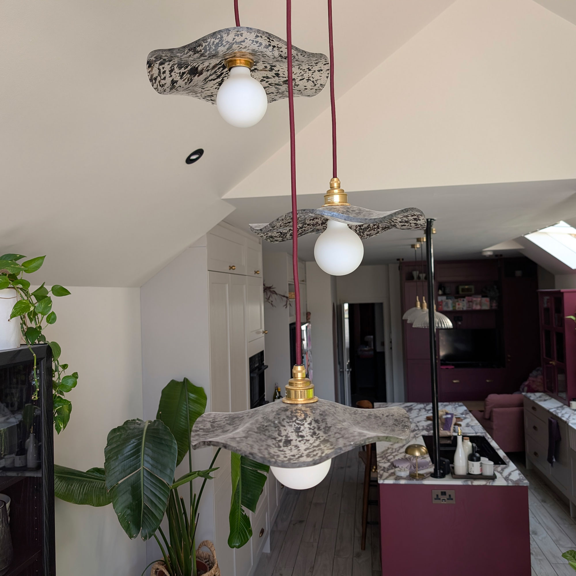 Three wavy glass pendant light shades hanging at different heights overlooking kitchen