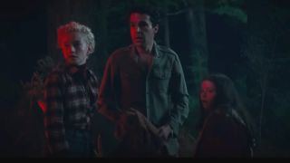 Julia Garner, Christopher Abbott and Matilda Firth are stunned in the dark forest bathed in red light in Wolf Man.